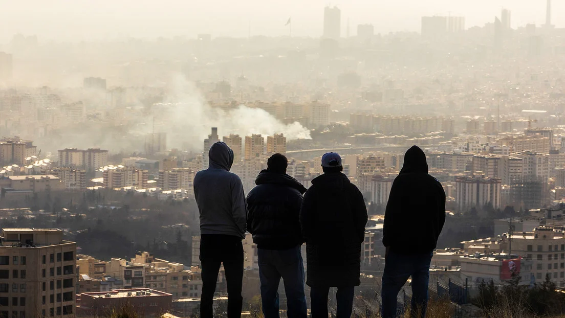 Hombres observan desde una ladera una columna de humo tras una explosión provocada por un ataque de EE.UU. e Israel contra Teherán, Irán, 2 de marzo de 2026